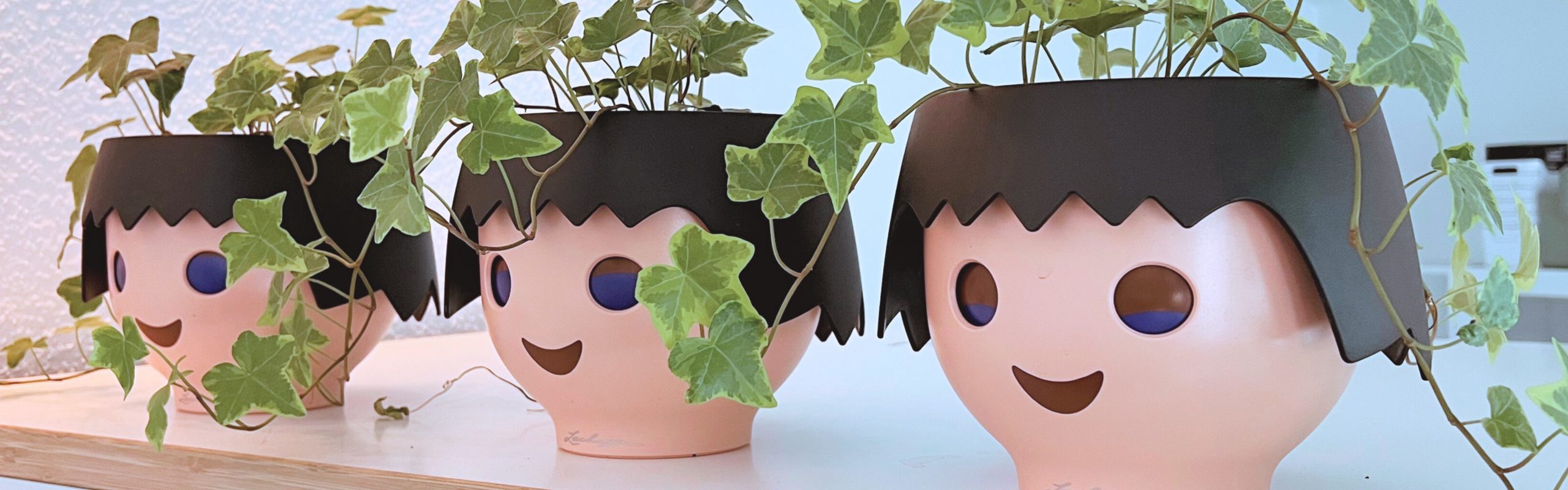 Drei Playmobil-Köpfe als Blumenübertöpfe. Darin wächst Efeu.